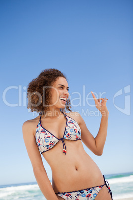 Young attractive woman standing on the beach while pointing her