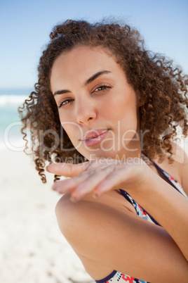 Young woman sending an air kiss while blowing on her hand