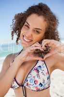 Smiling young woman making a heart with her hands