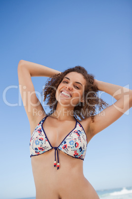 Young woman raising her arms above her head in front of the sea