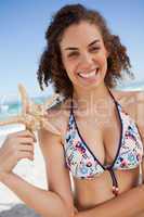 Smiling young woman discovering a starfish on the beach
