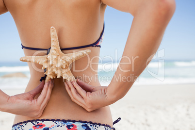 Rear view of a young woman holding a starfish on her back