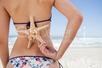 Young woman holding a starfish on her back with one hand