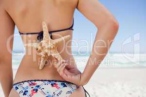 Young woman holding a starfish on her back with one hand