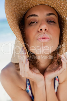 Young woman wearing a straw hat while puckering her lips