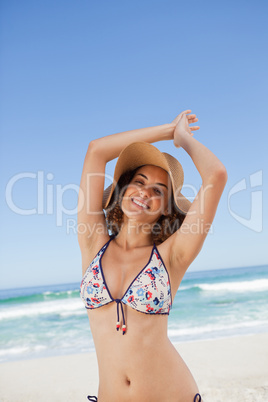Young happy woman in beachwear joining her hands above her head