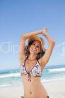 Young happy woman in beachwear joining her hands above her head