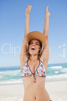 Young woman on the beach screaming with joy while raising her ar
