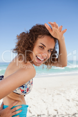 Young smiling woman placing her hand on her forehead to look at