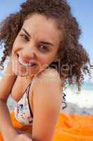 Young smiling woman lying down on a beach towel while staring at