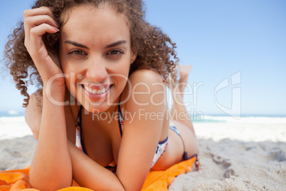 Young woman lying down while showing a great smile with her hand