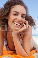 Smiling attractive woman lying down with hand on cheek