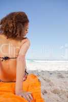 Rear view of a young woman sitting on a beach towel