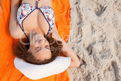 Overhead view of a smiling young woman lying on her beach towel
