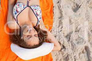 Overhead view of a smiling young woman lying on her beach towel