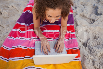Overhead view of a young woman using her laptop on her beach tow