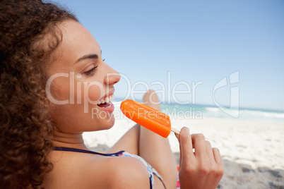 Young smiling woman holding a popsicle in front of the sea