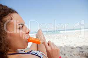 Young attractive woman eating a popsicle on the beach