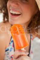 Orange popsicle held by a smiling young woman