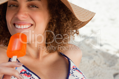 Young attractive woman going to eat an orange ice lolly on the b