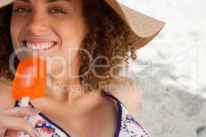 Young attractive woman going to eat an orange ice lolly on the b