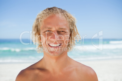 Young smiling man standing on the beach