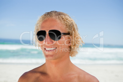Smiling man wearing sunglasses while standing on the beach