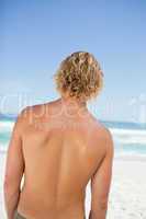 Rear view of a young blonde man looking at the ocean