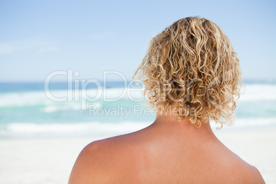 Rear view of a blonde man standing on the beach