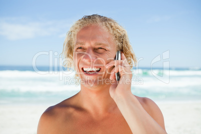Smiling man using his mobile phone while standing on the beach