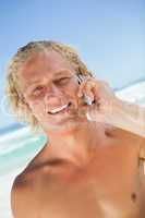 Smiling blonde man looking at the camera while calling with his