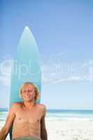 Smiling blonde man sunbathing on the beach with his surfboard ne