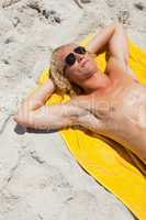 Overhead view of a blonde man lying on his beach towel