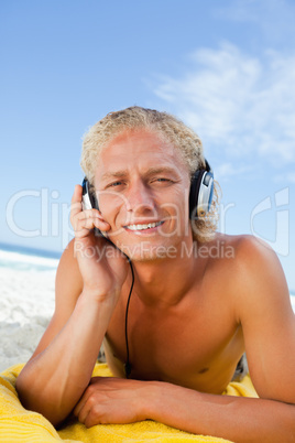 Young blonde man attentively listening to music with his headset