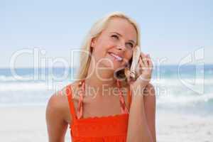 Young blonde woman listening to the sound of the sea through a s