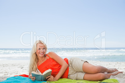 Young attractive woman lying on the side while holding a book