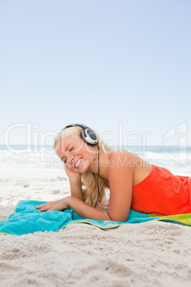 Young blonde woman lying down while listening to music