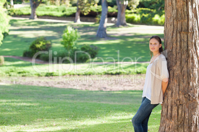 Woman leaning against a tree in the park