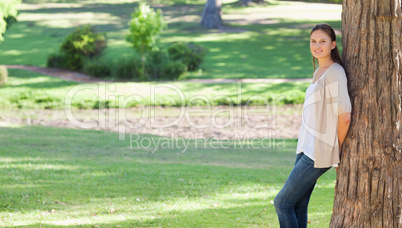 Woman leaning against a tree in the countryside