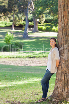 Woman in the countryside leaning against a tree