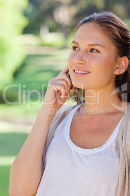 Smiling woman on her mobile phone in the park