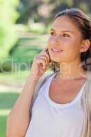 Smiling woman on her mobile phone in the park