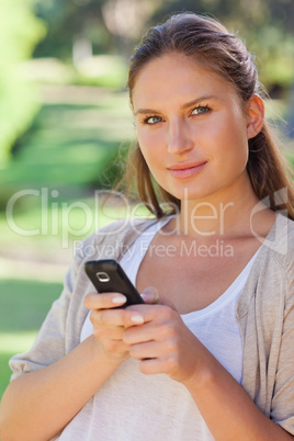 Close up of woman holding her cellphone in the park