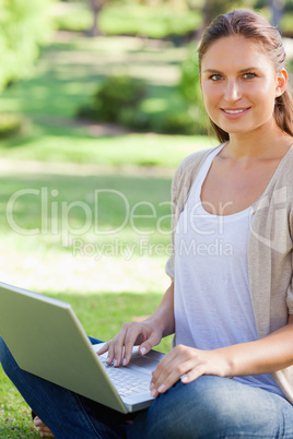 Smiling woman working on her laptop in the park