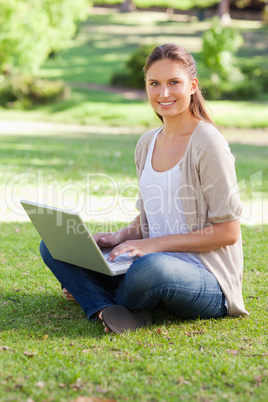 Smiling woman working on her notebook in the park