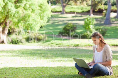Woman sitting on the lawn working on her notebook
