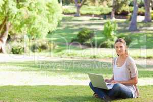 Woman with her laptop sitting in the park