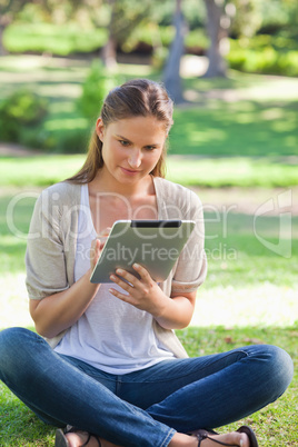 Woman sitting on the grass while using her tablet computer