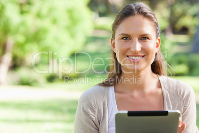 Smiling woman sitting on the lawn with a tablet computer