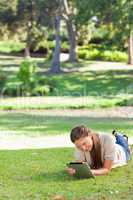 Woman laying on the lawn using a tablet computer